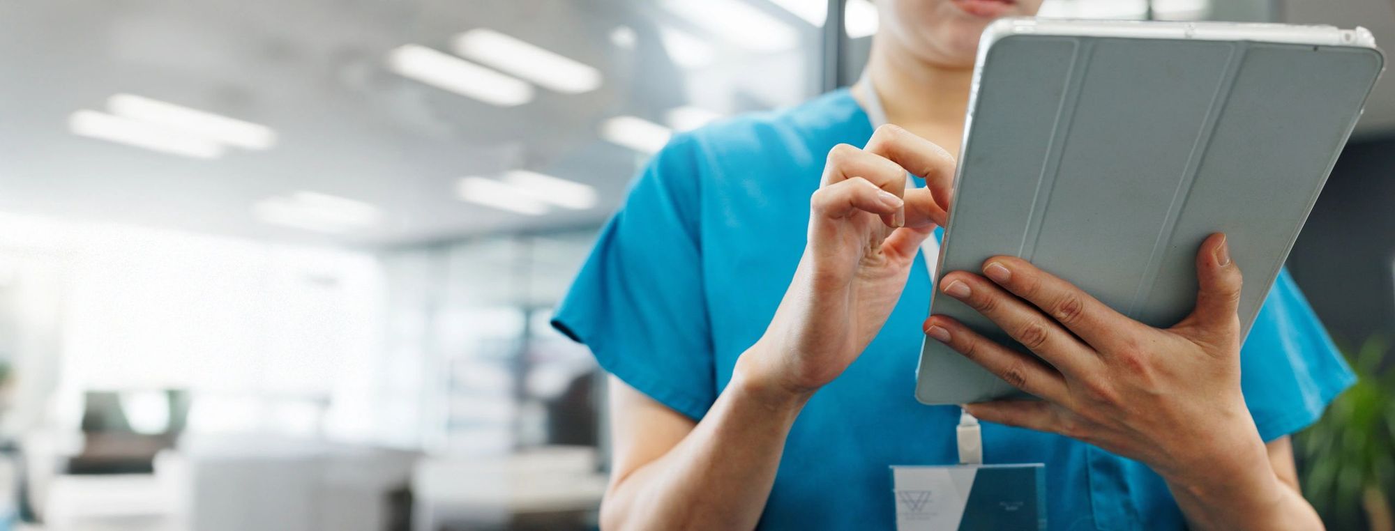 Friendly nurse in blue scrubs using a tablet
